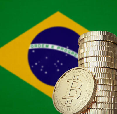 Brazilian flag with a stack of bitcoins in foreground