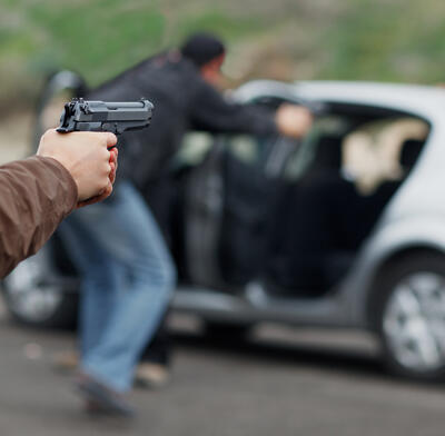 Man pointing hand gun at occupants of vehicle